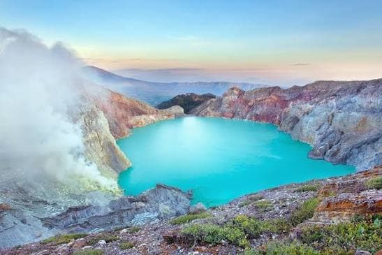 The turquoise acid crater lake of Kawah Ijen at dawn, sulphur steam drifting across the water
